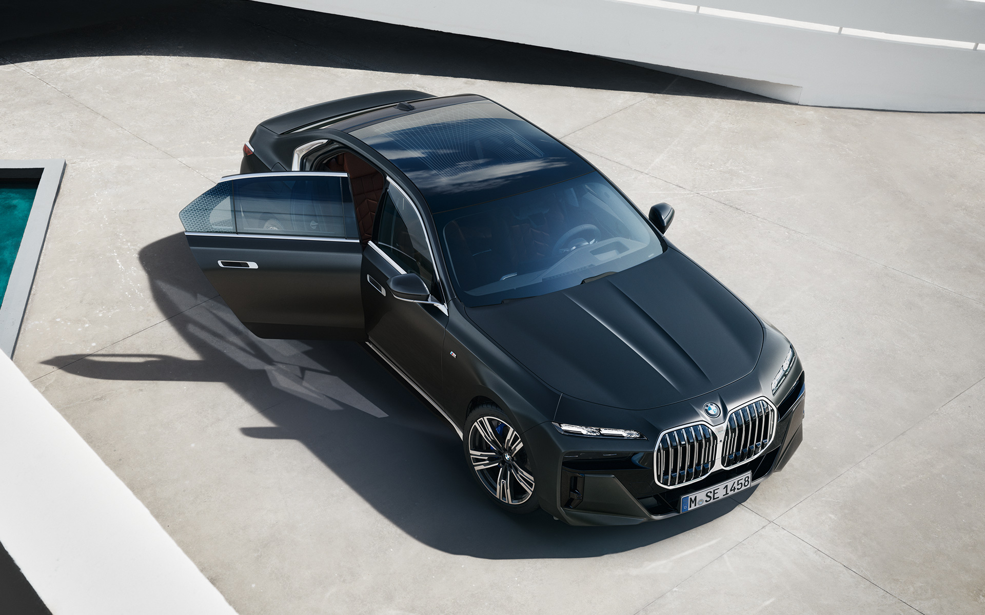 BMW řady 7 Sedan G70 ICE 740i M sportovní paket metalický lak Frozen Deep Grey (šedá) pohled shora s otevřenými dveřmi u spolujezdce