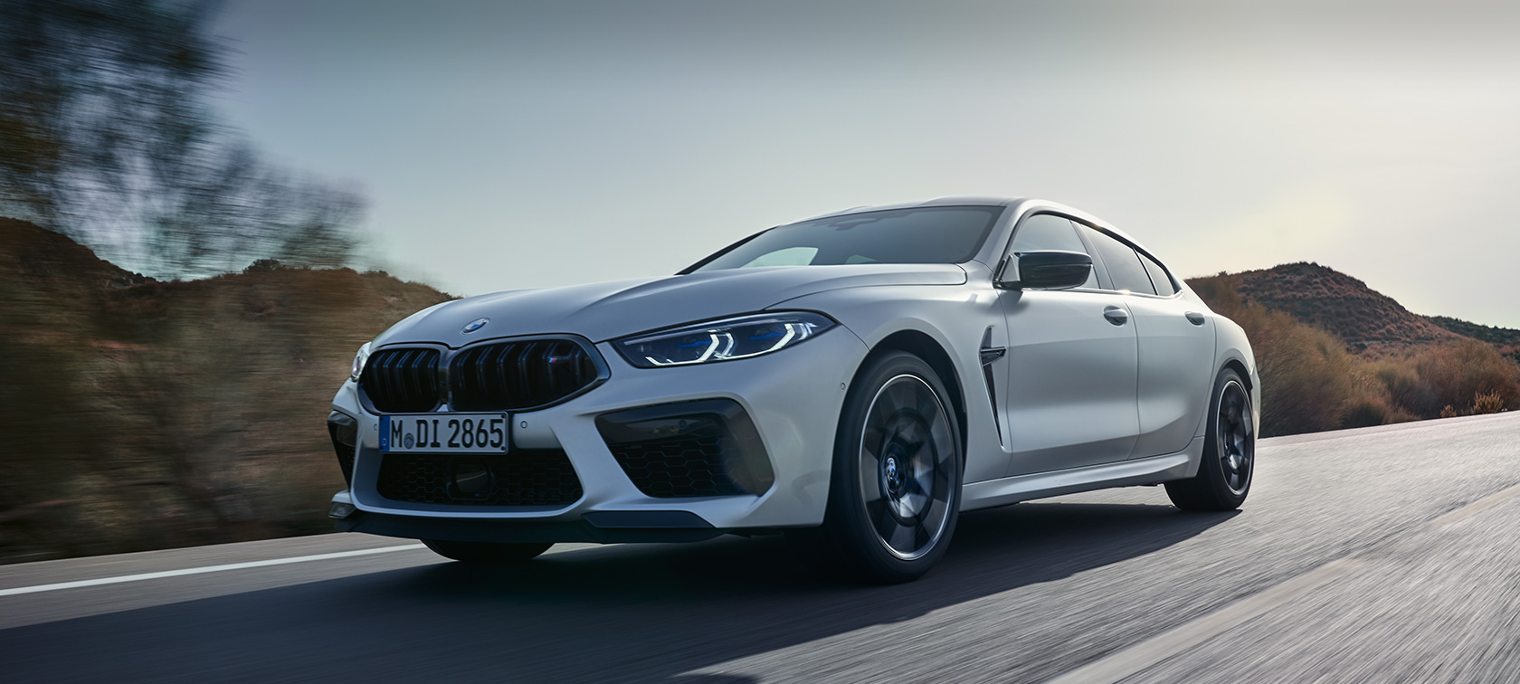 BMW M8 Competition Gran Coupé F93 LCI Facelift 2022 v metalické barvě BMW Invidividual Frozen Brilliant White (bílá) ze tříčtvrtečního pohledu zepředu při jízdě