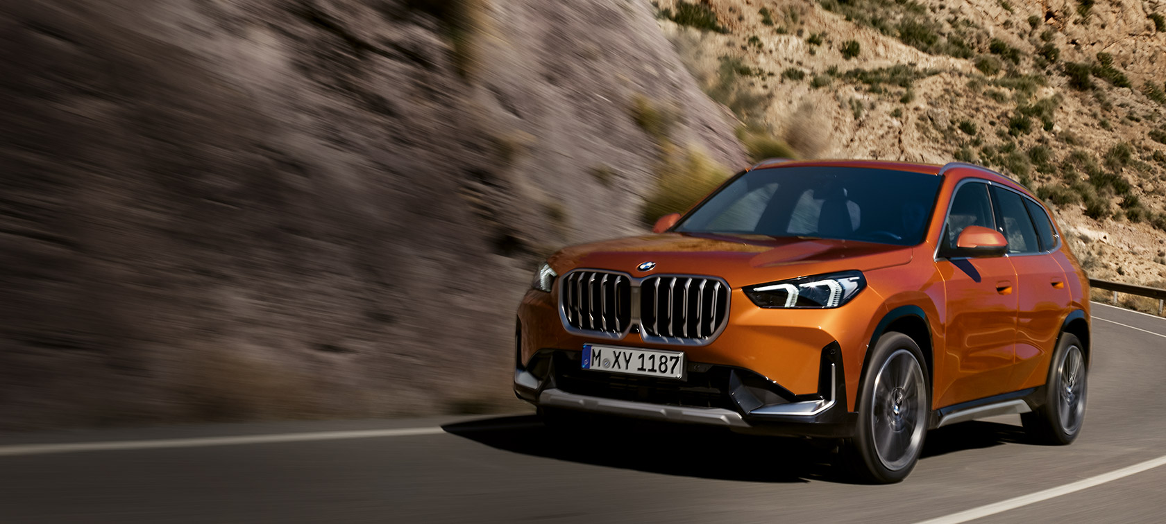 BMW X1 U11 xLine metalický lak Utah Orange (oranžová) tříčtvrteční pohled zepředu na okresní silnici